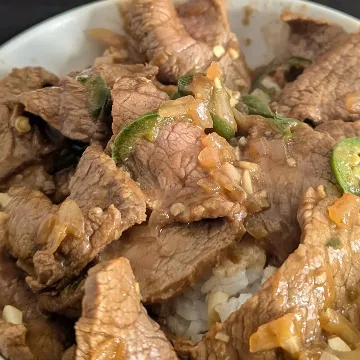 A beef bowl over rice with sliced green chilies