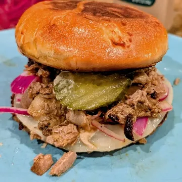 A brisket sandwich with pickles on a toasted bun