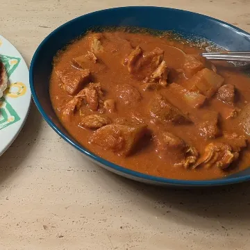 Indian curry in a deep blue bowl, with flatbread on the side