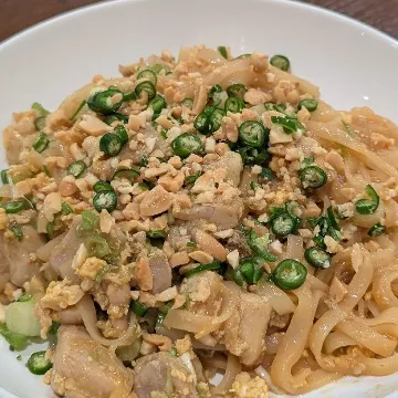 Pad thai topped with crushed peanuts and green chilies