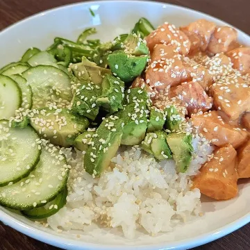A poke bowl with salmon, avocado, cucumber and sesame over rice