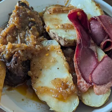 Ribs and baked potato halves in a glossy sauce