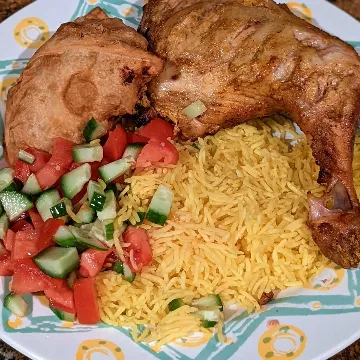 Tandoori chicken with yellow rice and a tomato and cucumber salad